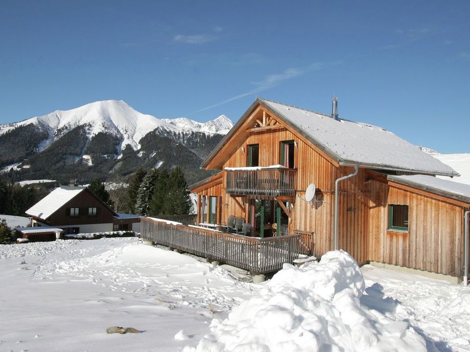 Holzhaus mit Schnee bedeckt, Berge im Hintergrund